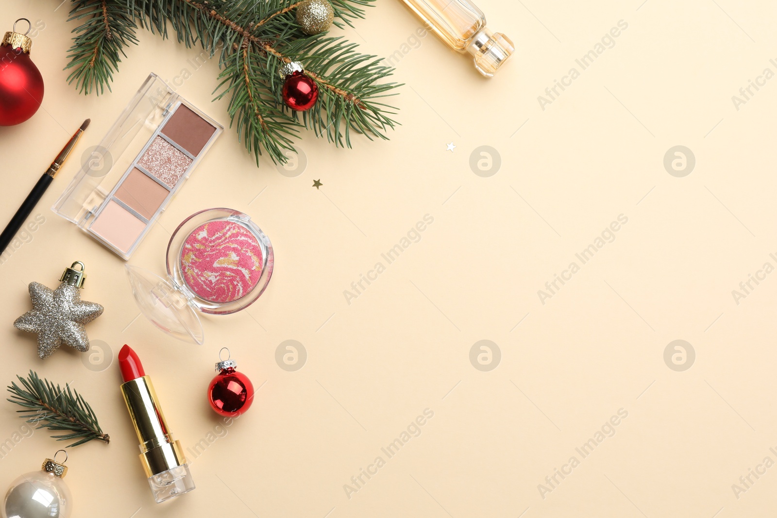 Photo of Flat lay composition with makeup products and Christmas decor on beige background. Space for text