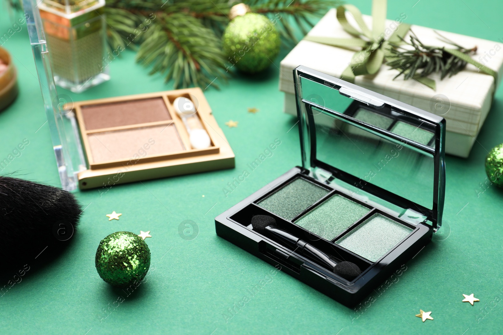 Photo of Different makeup products and Christmas decor on green background, closeup