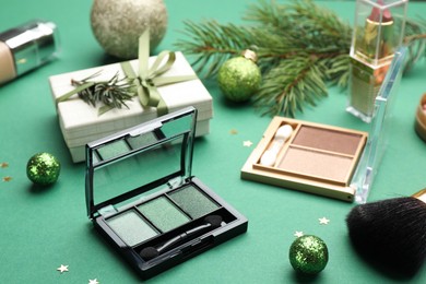 Photo of Different makeup products and Christmas decor on green background, closeup