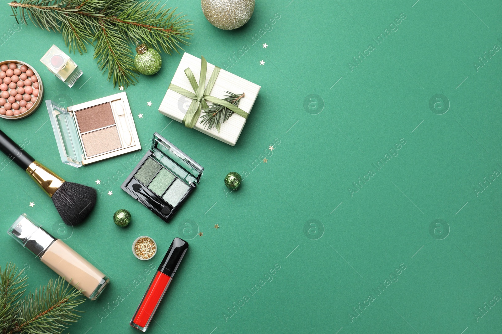 Photo of Flat lay composition with makeup products and Christmas decor on green background. Space for text