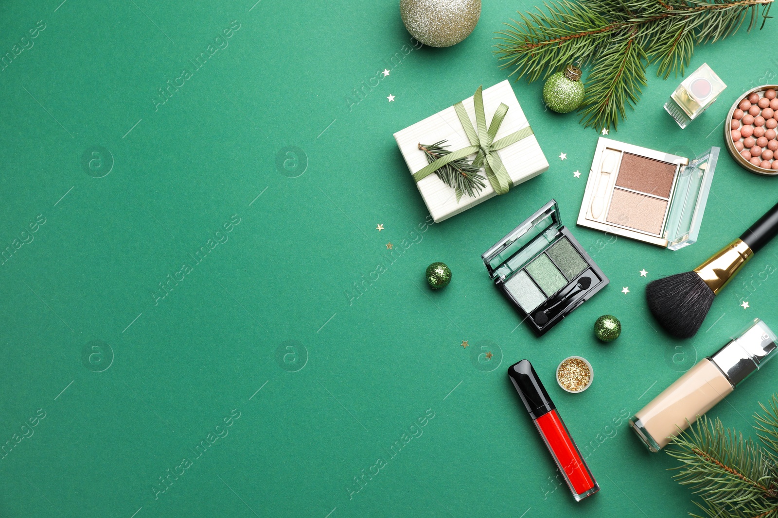 Photo of Flat lay composition with makeup products and Christmas decor on green background. Space for text