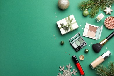 Photo of Flat lay composition with makeup products and Christmas decor on green background. Space for text