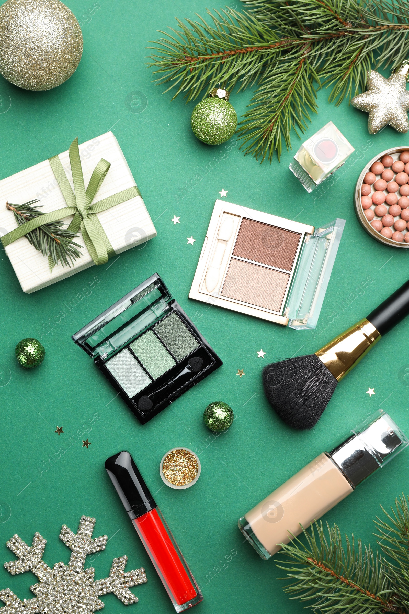 Photo of Flat lay composition with makeup products and Christmas decor on green background