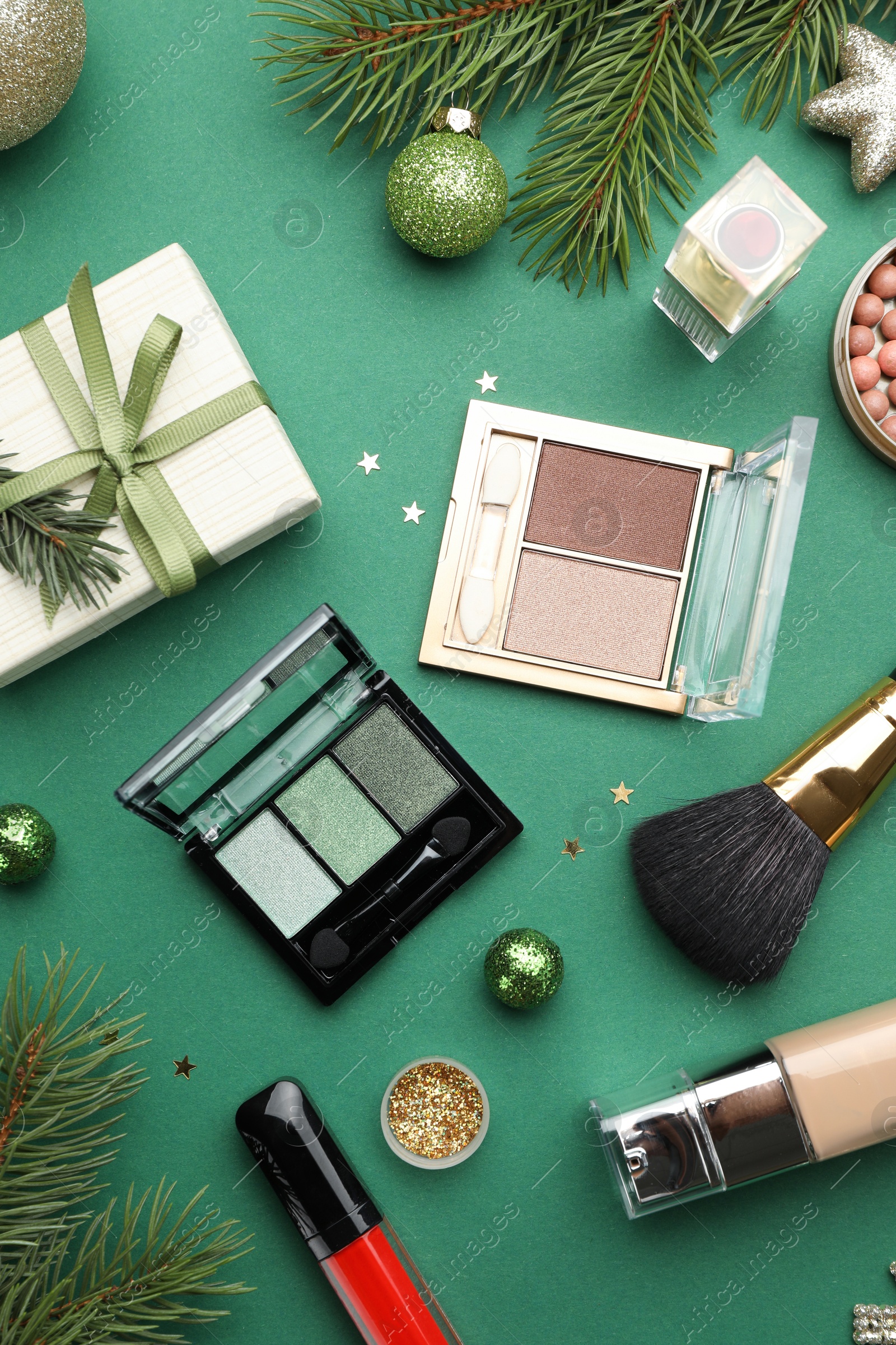 Photo of Flat lay composition with makeup products and Christmas decor on green background