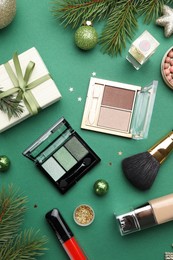 Photo of Flat lay composition with makeup products and Christmas decor on green background