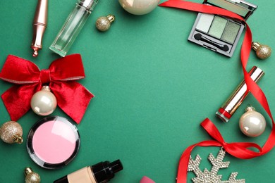 Photo of Frame made of makeup products and Christmas decor on green background, flat lay. Space for text