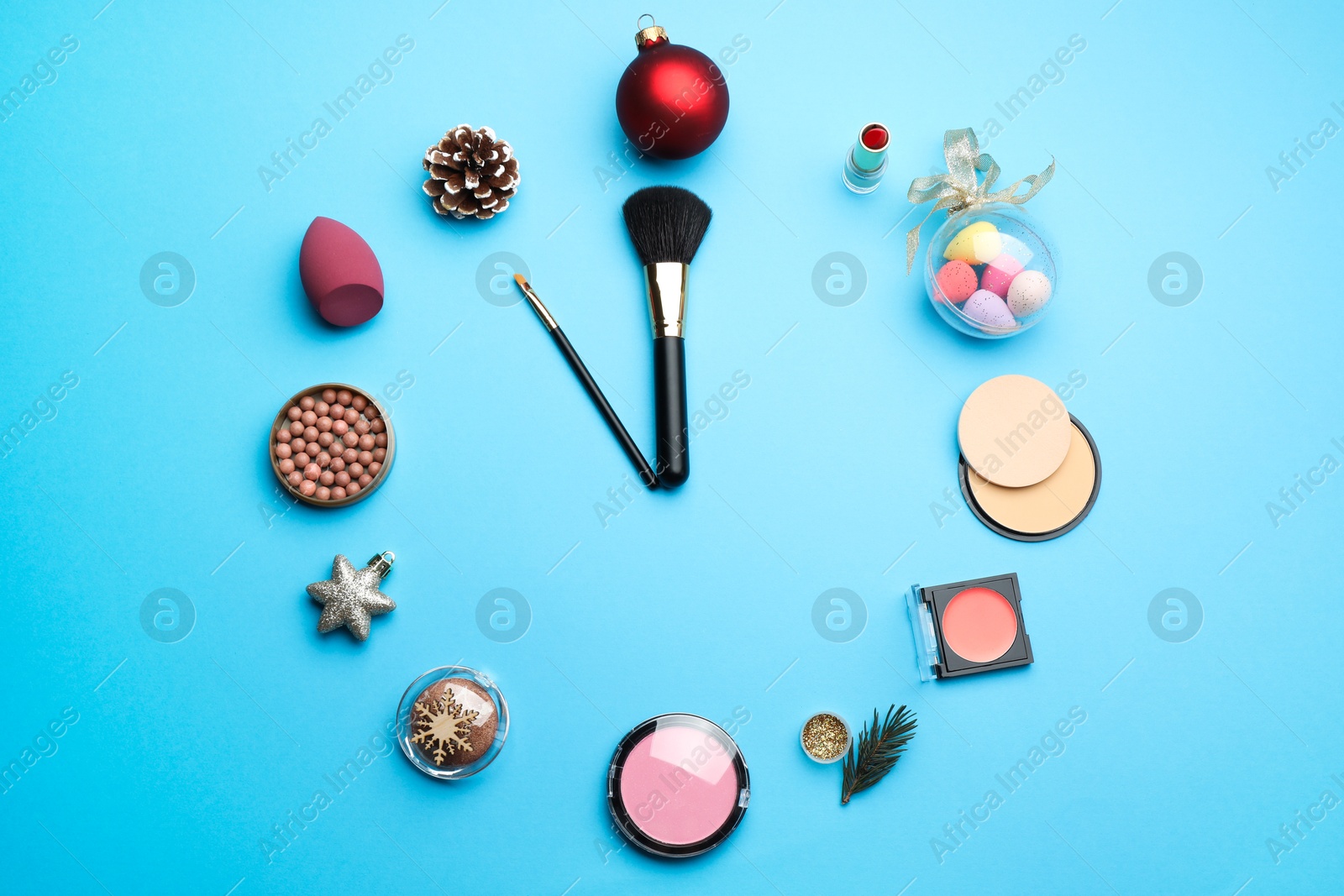 Photo of Clock made of decorative cosmetic products and festive decor on light blue background, flat lay