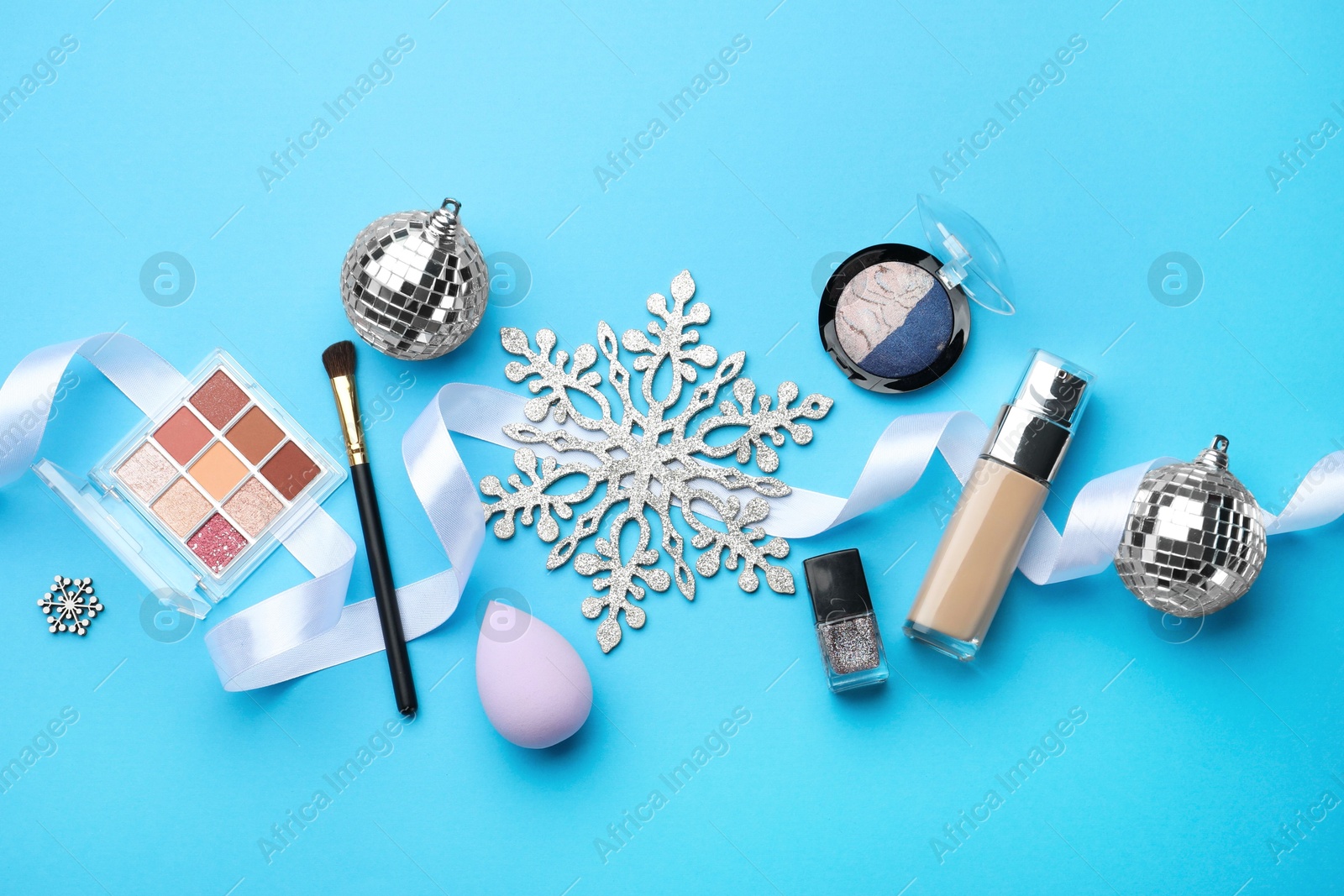 Photo of Flat lay composition with makeup products and Christmas decor on light blue background