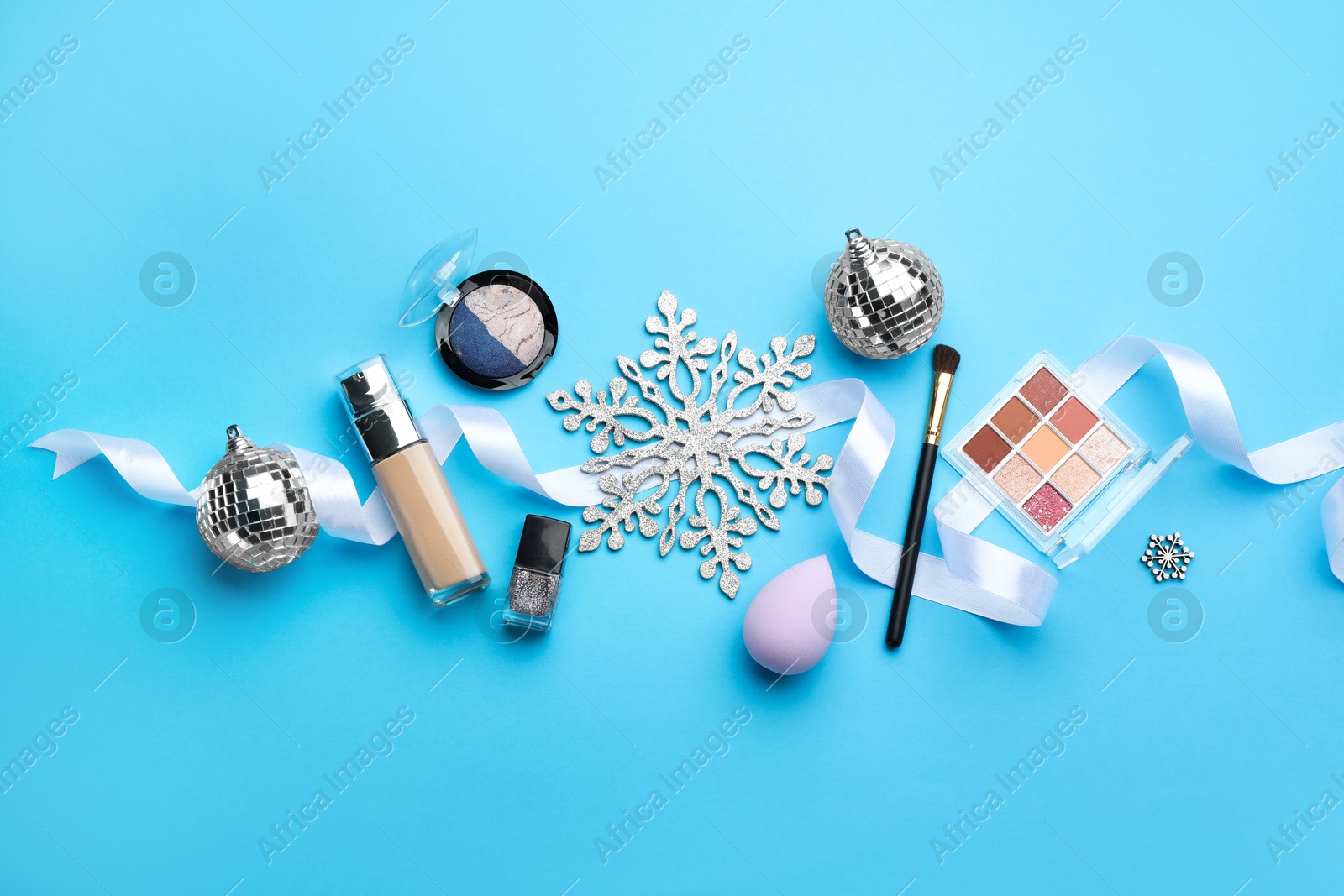 Photo of Flat lay composition with makeup products and Christmas decor on light blue background