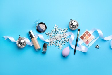 Photo of Flat lay composition with makeup products and Christmas decor on light blue background