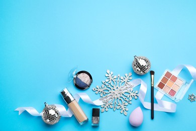 Photo of Flat lay composition with makeup products and Christmas decor on light blue background. Space for text