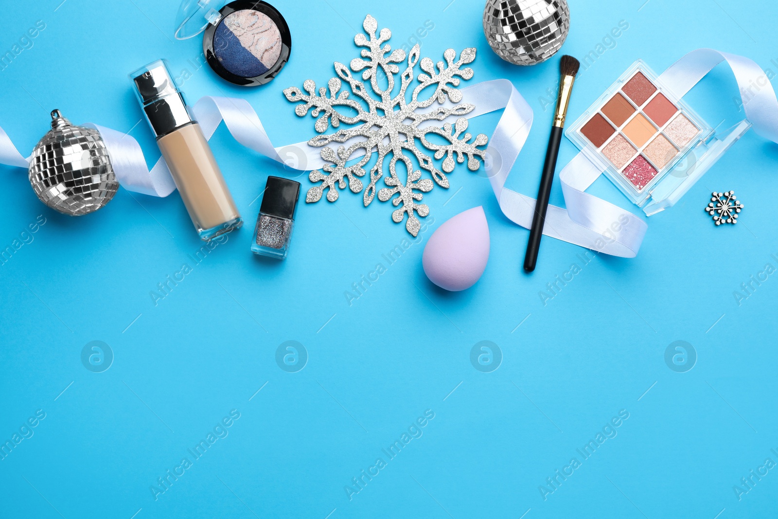 Photo of Flat lay composition with makeup products and Christmas decor on light blue background. Space for text