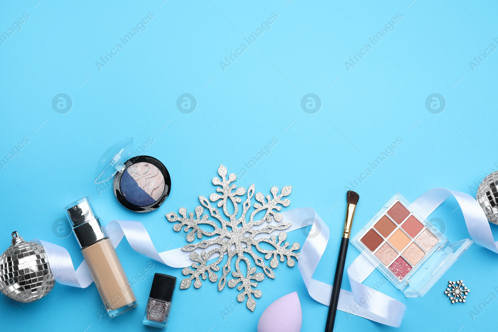 Photo of Flat lay composition with makeup products and Christmas decor on light blue background. Space for text