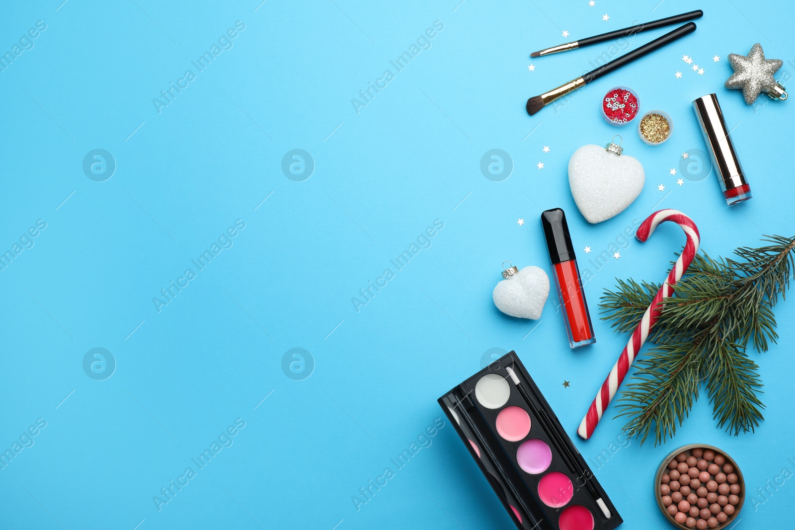 Photo of Flat lay composition with makeup products and Christmas decor on light blue background. Space for text