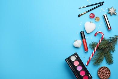 Photo of Flat lay composition with makeup products and Christmas decor on light blue background. Space for text