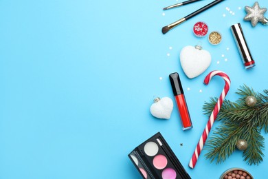 Photo of Flat lay composition with makeup products and Christmas decor on light blue background. Space for text