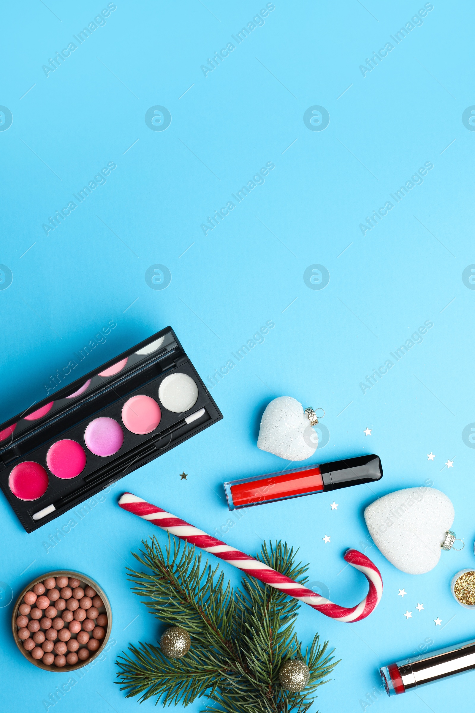 Photo of Flat lay composition with makeup products and Christmas decor on light blue background. Space for text