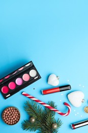 Photo of Flat lay composition with makeup products and Christmas decor on light blue background. Space for text