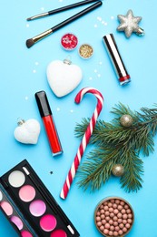 Photo of Flat lay composition with makeup products and Christmas decor on light blue background