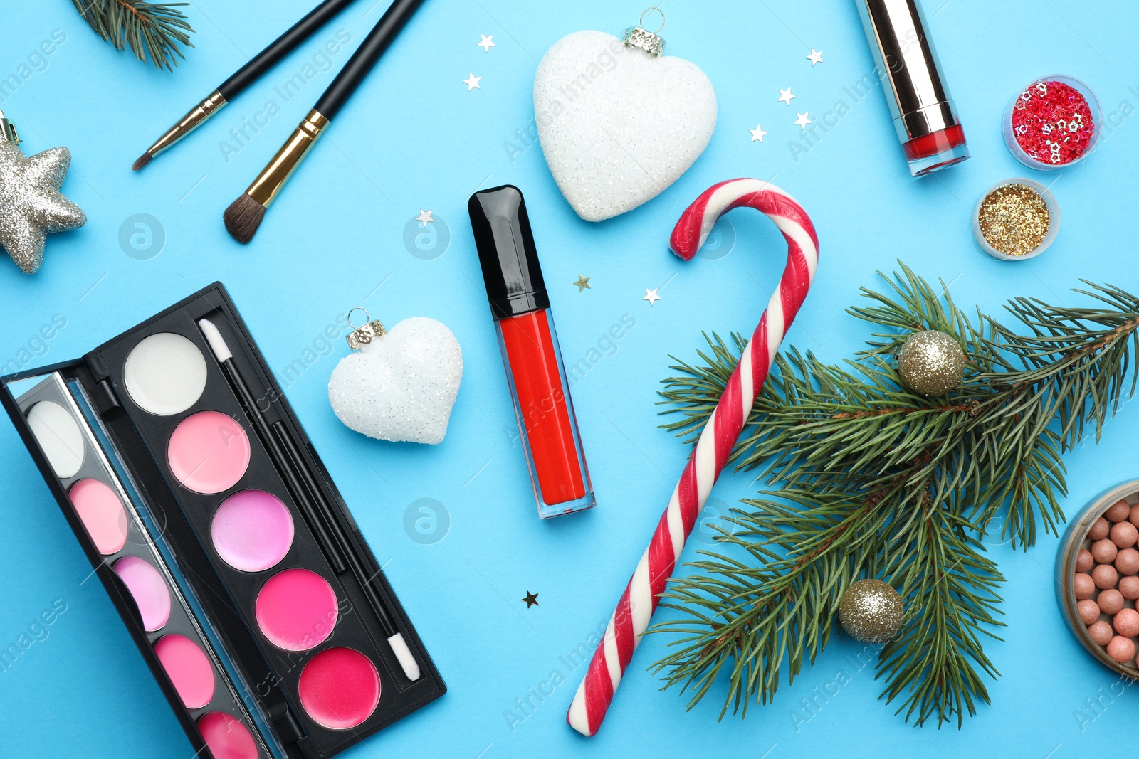 Photo of Flat lay composition with makeup products and Christmas decor on light blue background