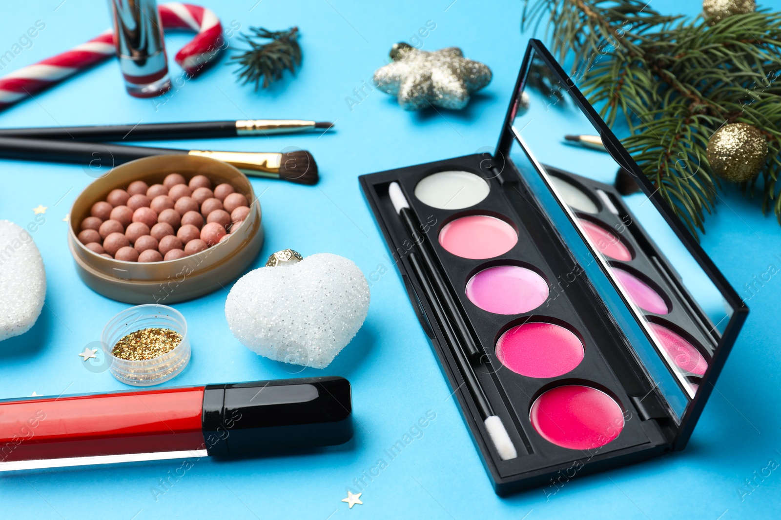 Photo of Different makeup products and Christmas decor on light blue background, closeup