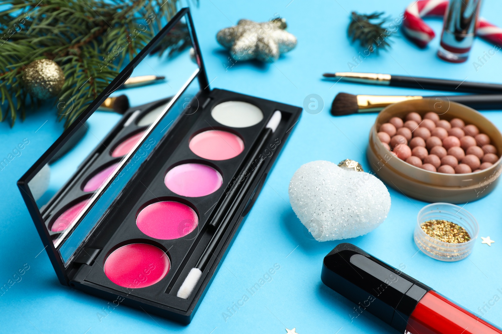 Photo of Different makeup products and Christmas decor on light blue background, closeup