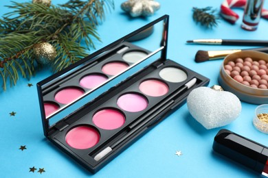 Photo of Different makeup products and Christmas decor on light blue background, closeup