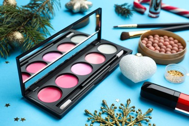 Photo of Different makeup products and Christmas decor on light blue background, closeup