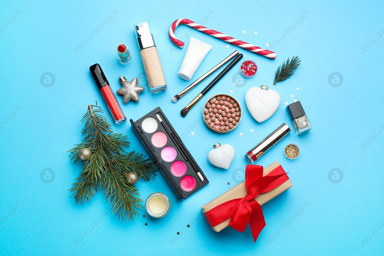 Photo of Flat lay composition with makeup products and Christmas decor on light blue background