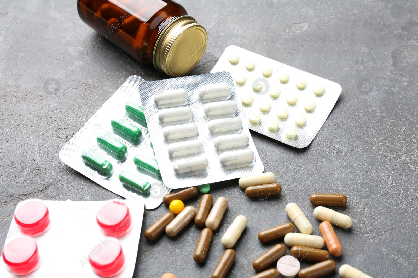 Photo of Pharmacist. Different pills and plastic bottle on grey table, closeup