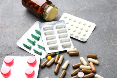 Pharmacist. Different pills and plastic bottle on grey table, closeup