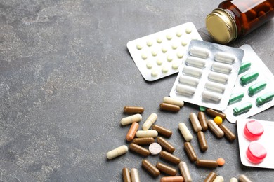 Photo of Pharmacist. Different pills and plastic bottle on grey table, space for text