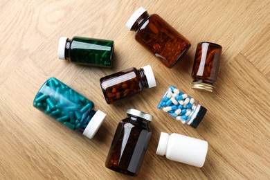 Photo of Pharmacist. Different pills in plastic bottles on wooden table, flat lay