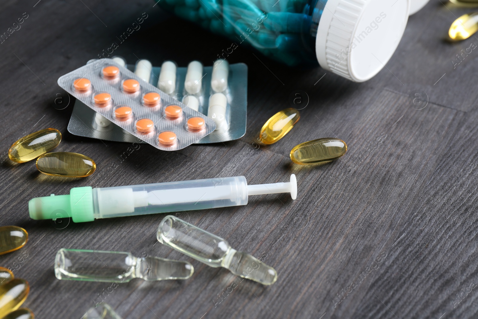 Photo of Pharmacist. Different pills, syringe and ampoules on grey wooden table, closeup