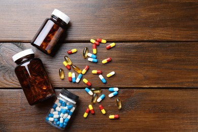 Photo of Pharmacist. Different pills and plastic bottles on wooden table, flat lay