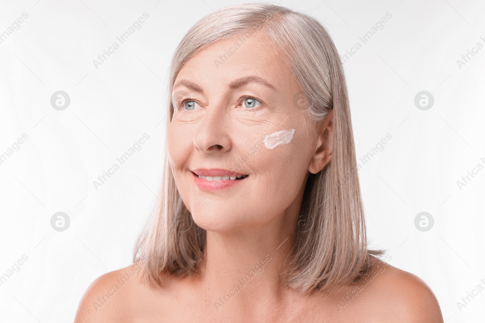 Photo of Senior woman with face cream on white background