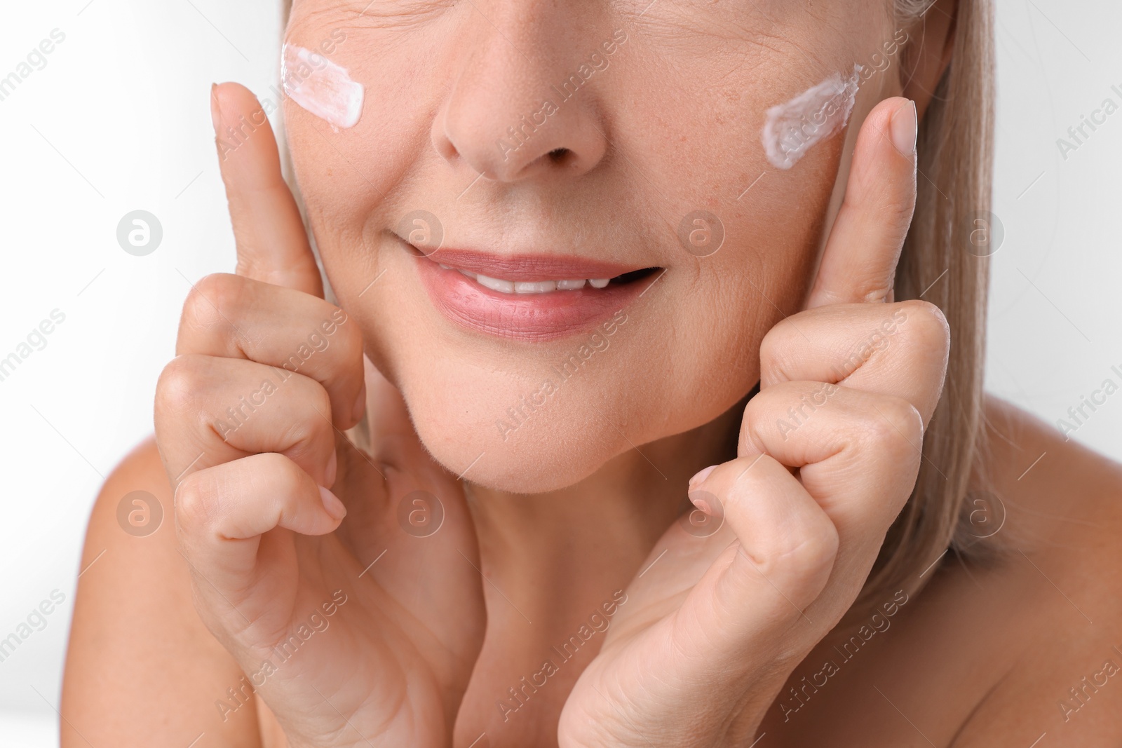 Photo of Senior woman with face cream on white background, closeup