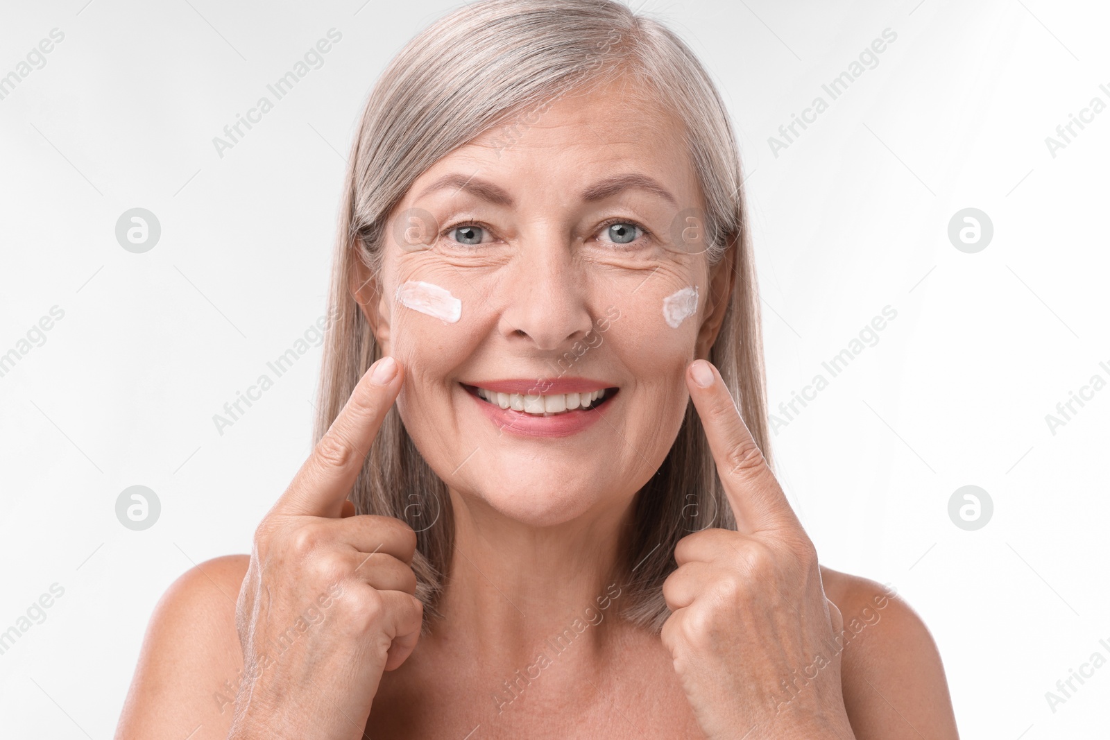 Photo of Senior woman with face cream on white background