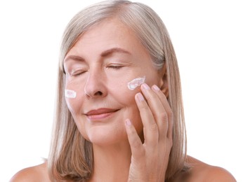 Senior woman applying face cream on white background