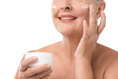 Photo of Senior woman applying face cream on white background, closeup