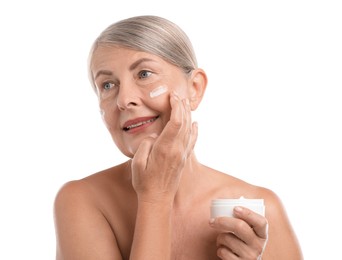 Photo of Senior woman applying face cream on white background