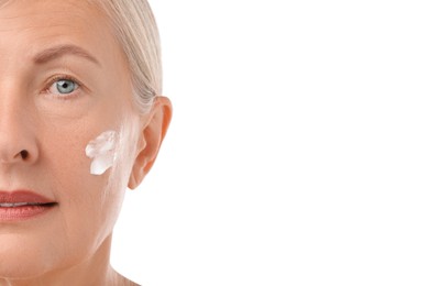 Senior woman with face cream on white background, closeup