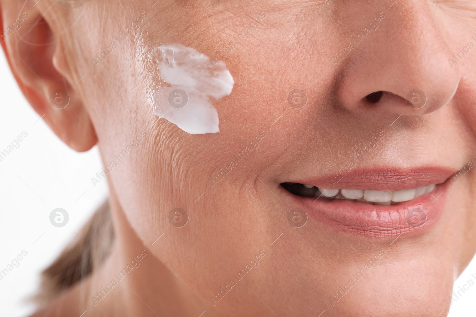 Photo of Senior woman with face cream on white background, closeup