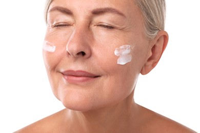 Senior woman with face cream on white background, closeup