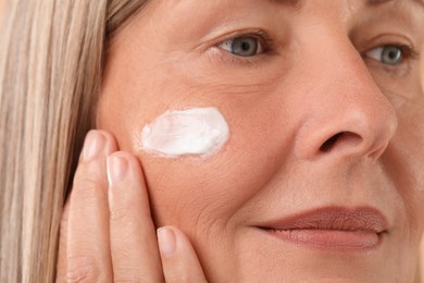 Photo of Senior woman with cream on face, closeup