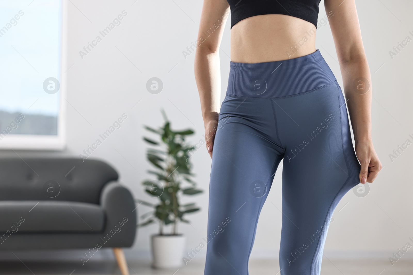 Photo of Woman wearing blue sports leggings indoors, closeup