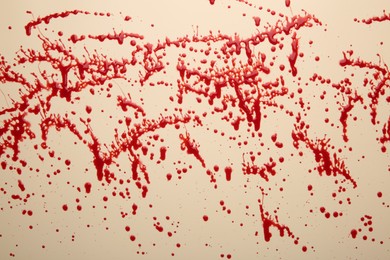 Photo of Splashes of red blood on beige background