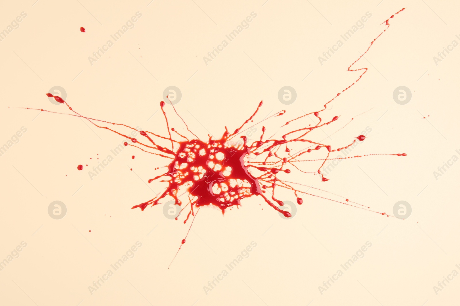 Photo of Splash of red blood on beige background