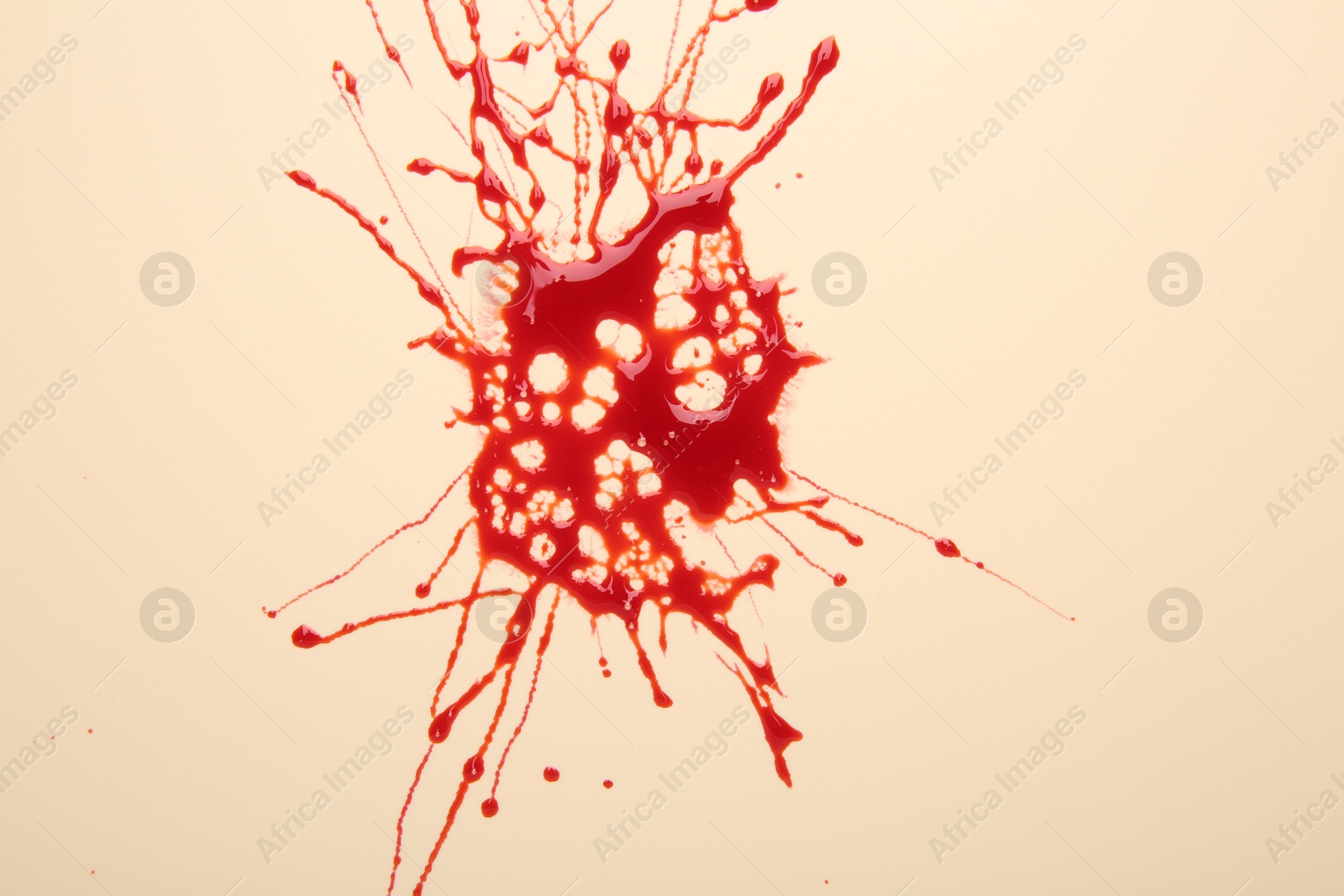 Photo of Splash of red blood on beige background