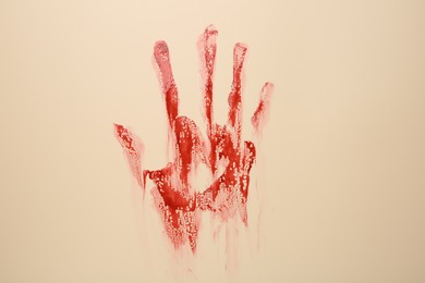 Photo of Bloody hand print of human on beige background